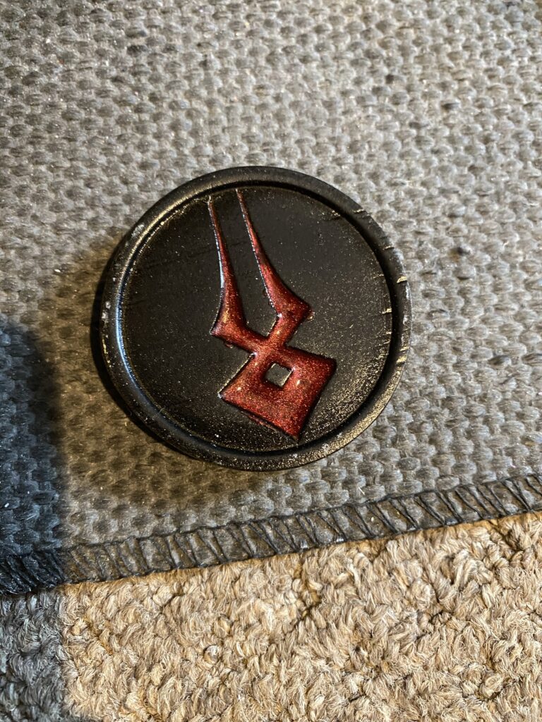 Red shimmering inlay on a black coin.