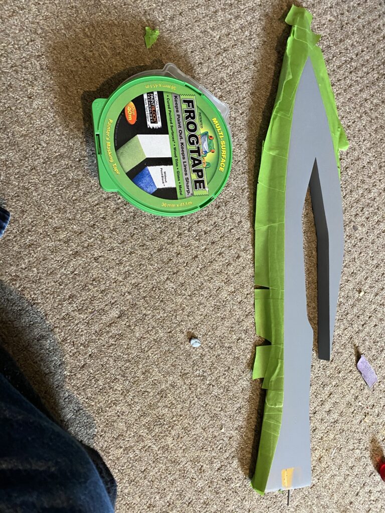 Green tape being applied to the bladed edge. Tap is green, rest of the item is primed grey. Capet definitely needs a hoover...