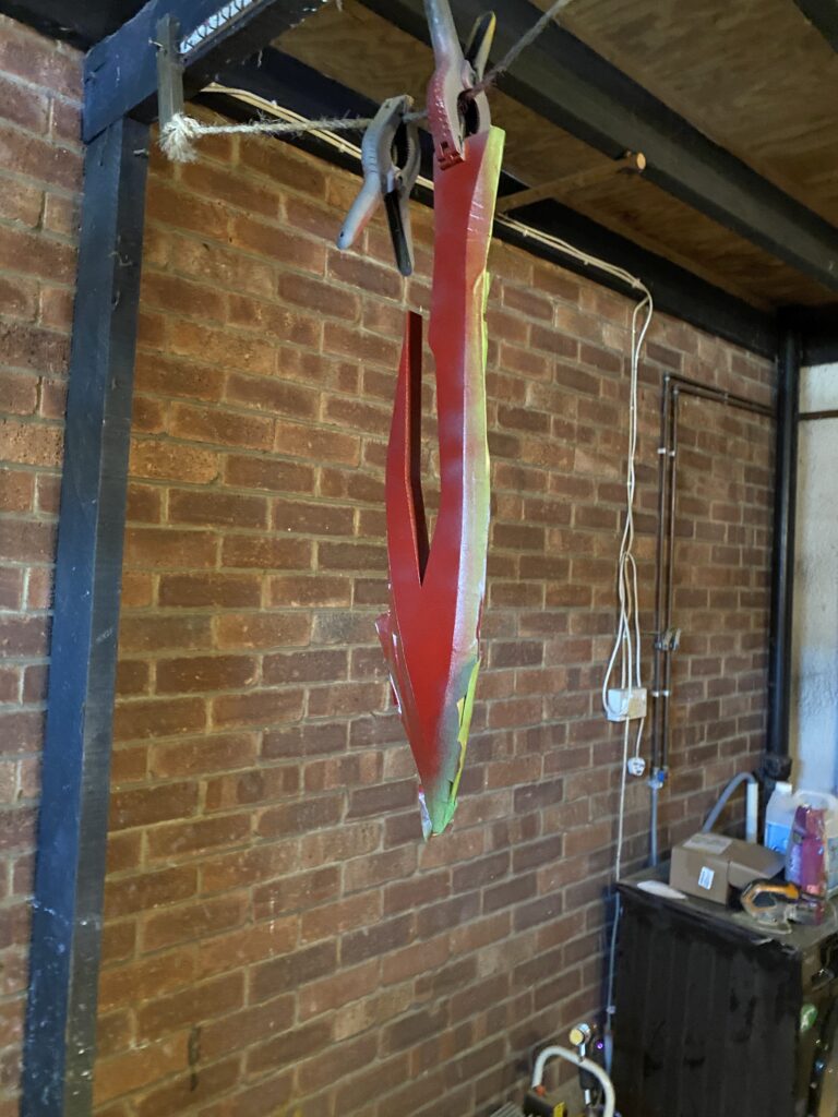 The sword being sprayed red while hanging from a rope