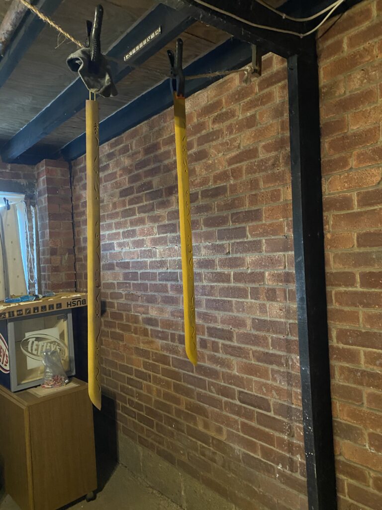 Two blades hanging from the rafters of a garage having just been sanded and primed. This is prototype one and two.