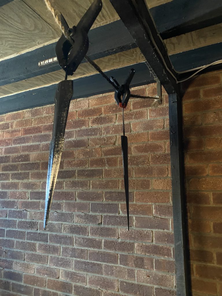 Two blades hanging from the rafters after their first coat of silver paint.