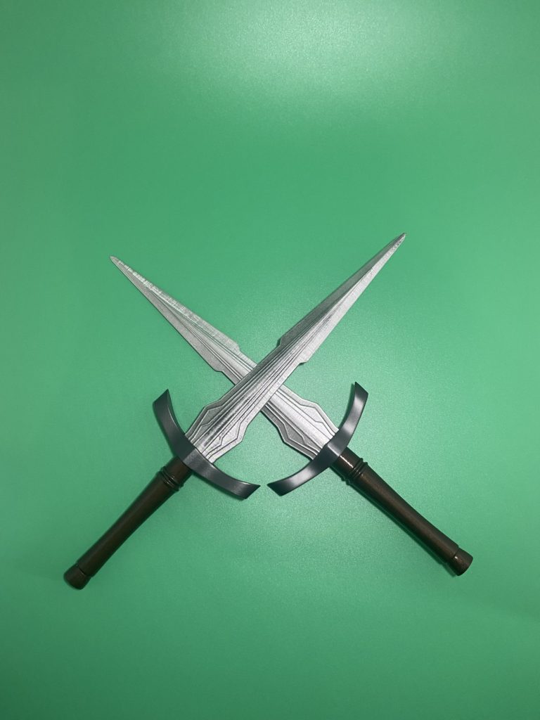 Two finished daggers in a cross on a green background.