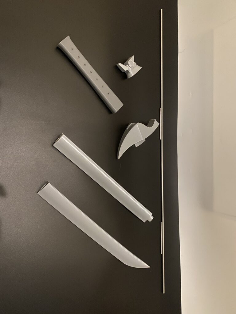 Yones Wind Sword components laid out. Grey PLA with a black background.