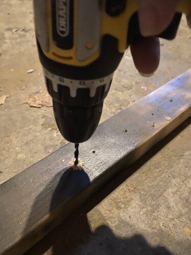 Drilling a few 4mm holes into a scrap piece of wood to make it easier to spray paint certain parts.