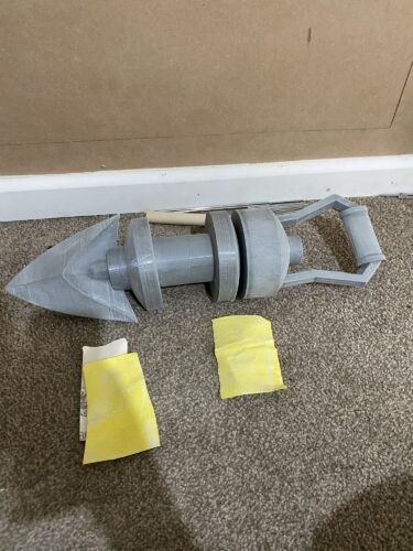 Mid sanding of the Longshot from Zelda, Ocarina of Time. The item is laid out half sanded with thbe sandpaper in front of it.