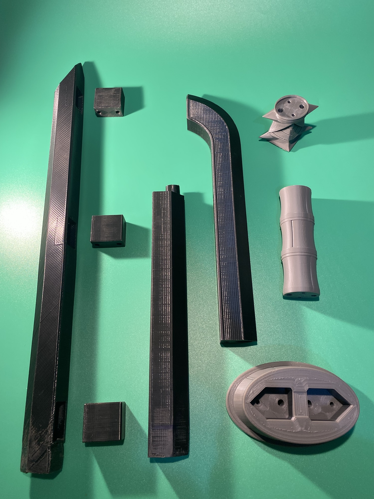 All printed parts of the Raw Build Kit for the Razor Sword from Zelda Majora's Mask, printed in grey and black PLA on a green background.