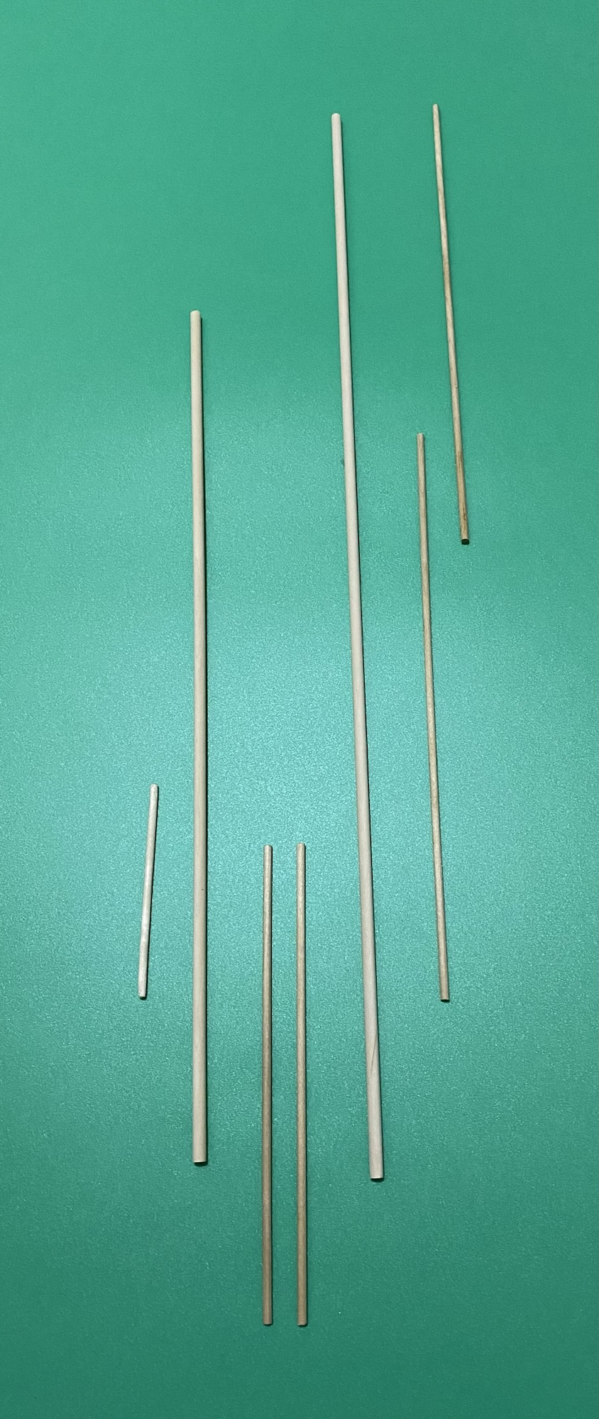 A number of wooden dowel intended for support rods ona green background.